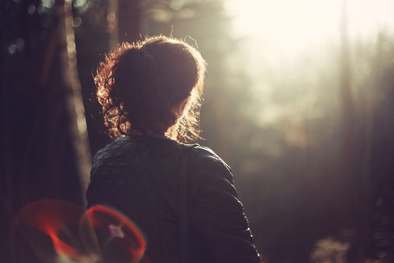 Frau im Wald von hinten sichtbar im sanften Licht