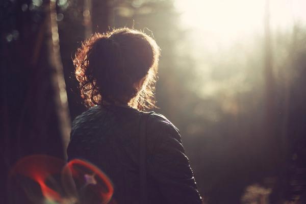 Frau im Wald von hinten sichtbar im sanften Licht
