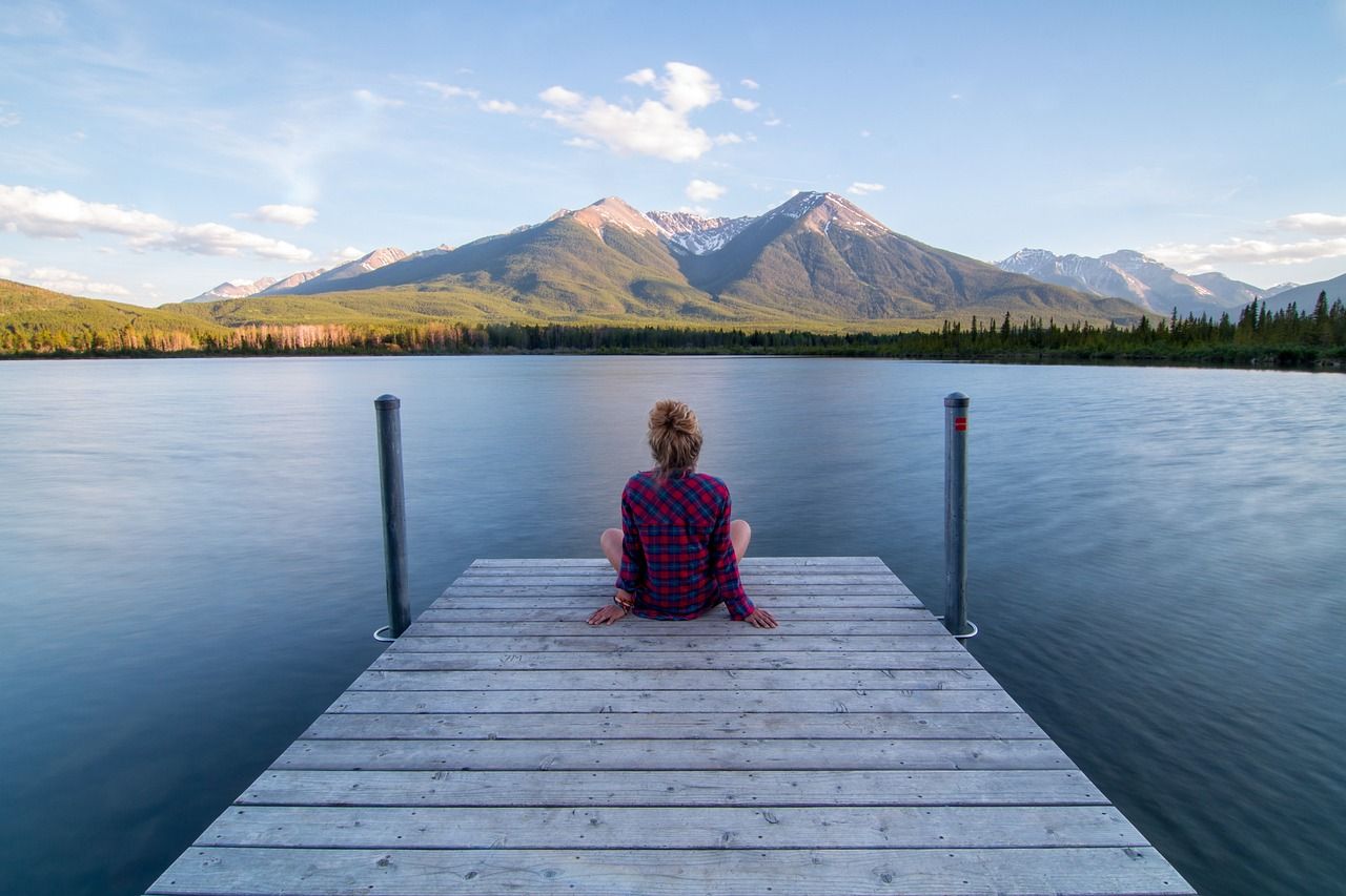 Frau auf einem Steg am Wasser mit Blick auf die Berge als Sinnbild für die Wirkung des Vagusnerv bei Stress