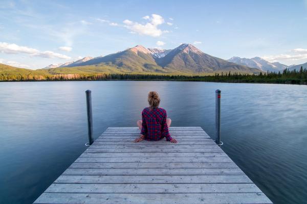 Frau auf einem Steg am Wasser mit Blick auf die Berge als Sinnbild für die Wirkung des Vagusnerv bei Stress