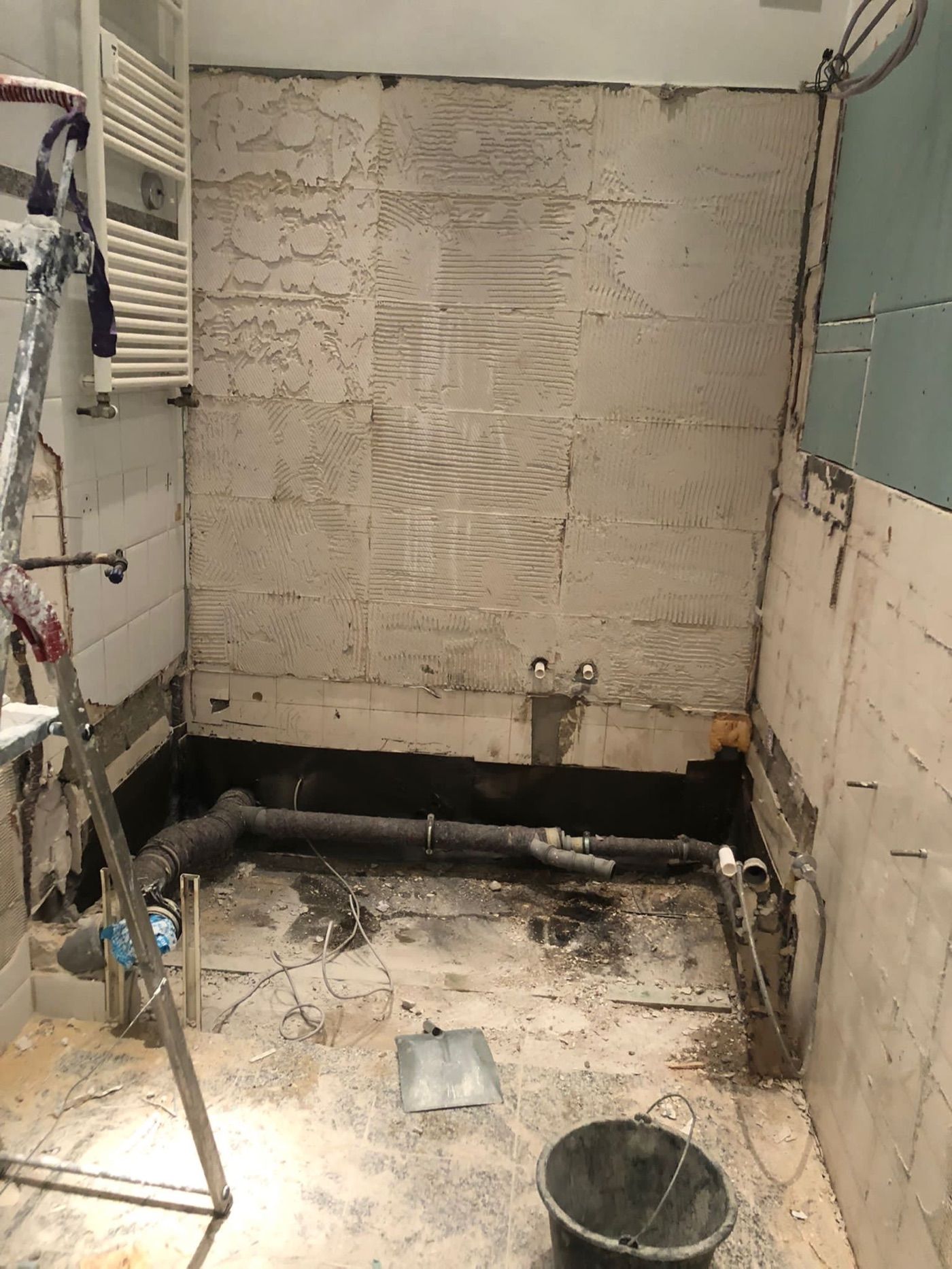 Dasselbe Bad im Rohbau: Wände bis auf den Fliesenkleber abgeschlagen, die Abwasserleitungen liegen frei.