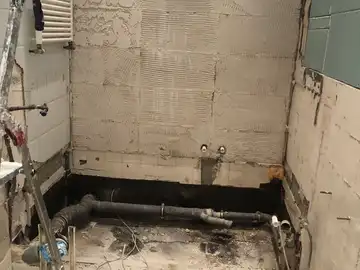 Dasselbe Bad im Rohbau: Wände bis auf den Fliesenkleber abgeschlagen, die Abwasserleitungen liegen frei.