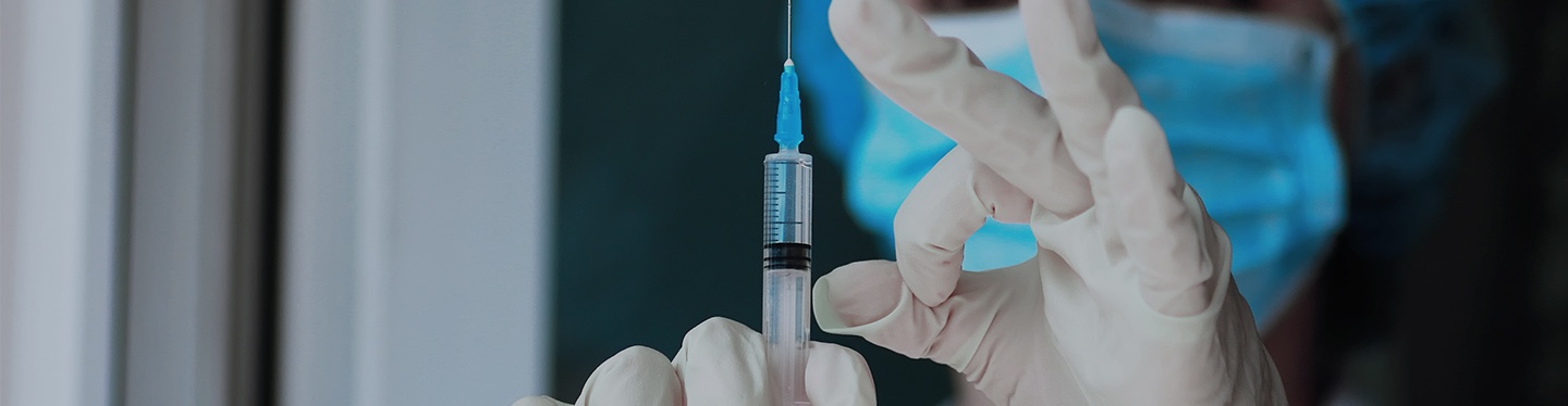 Sjuksköterska som håller i en spruta.