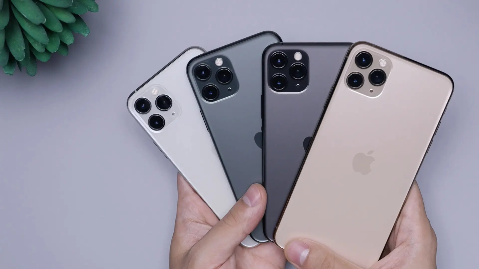 Person håller upp fyra Iphone-mobiler i en fjäderformation. 