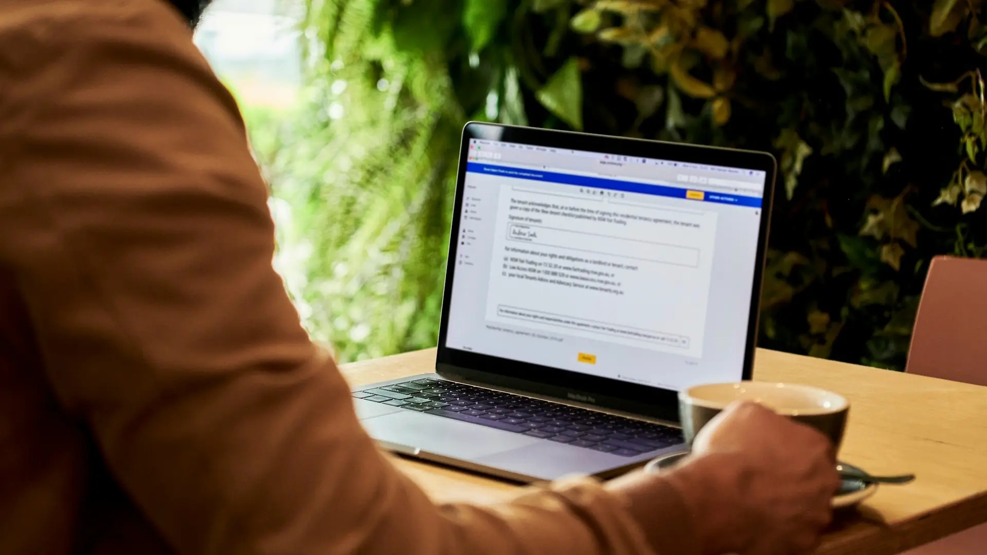 En dator med ett dokument på ett bord med en kaffekopp.