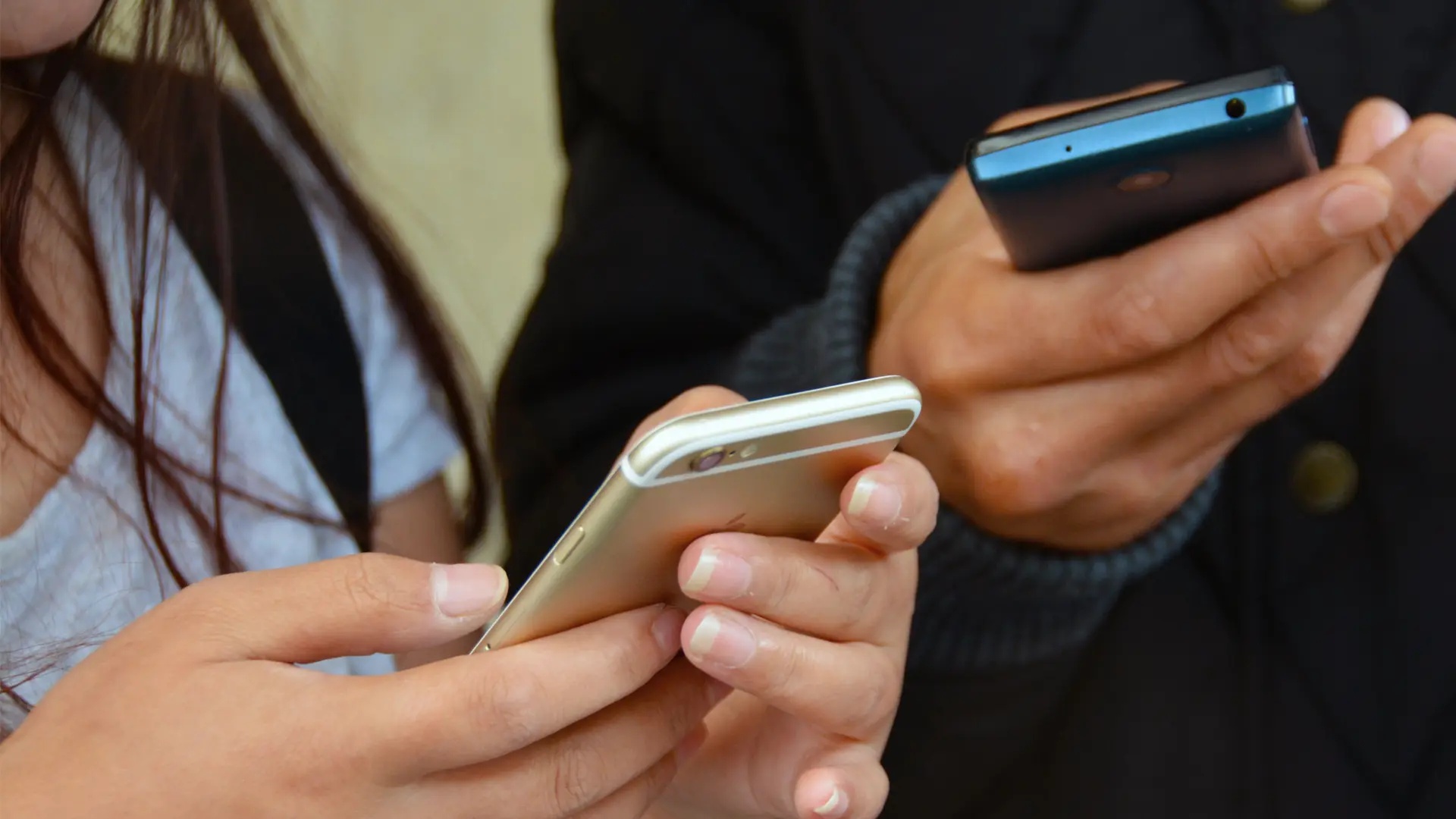 Närbild på två personer som läser något på sina mobiler.