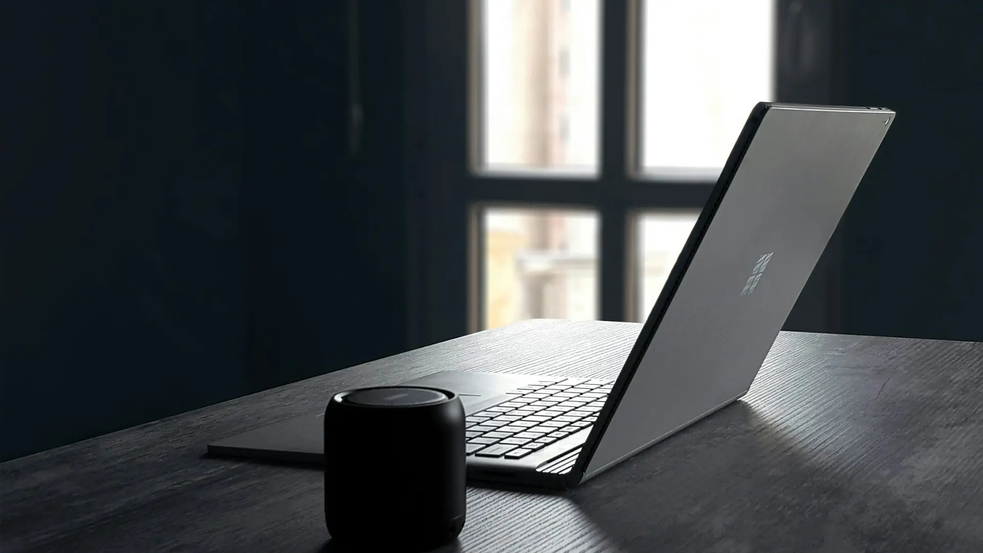 Mörk bild med Windows-dator på ett bord.