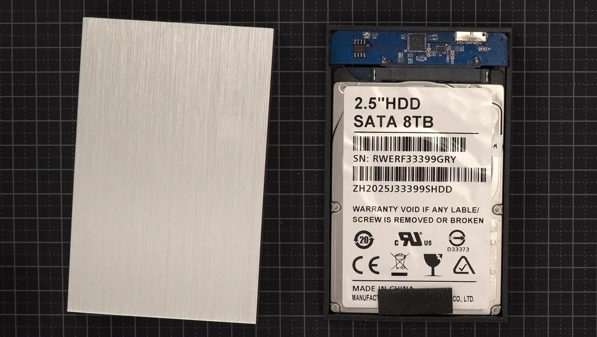 En uppskruvad extern hårddisk. På en slarvigt klistrad etikett står ”SATA 8TB”.