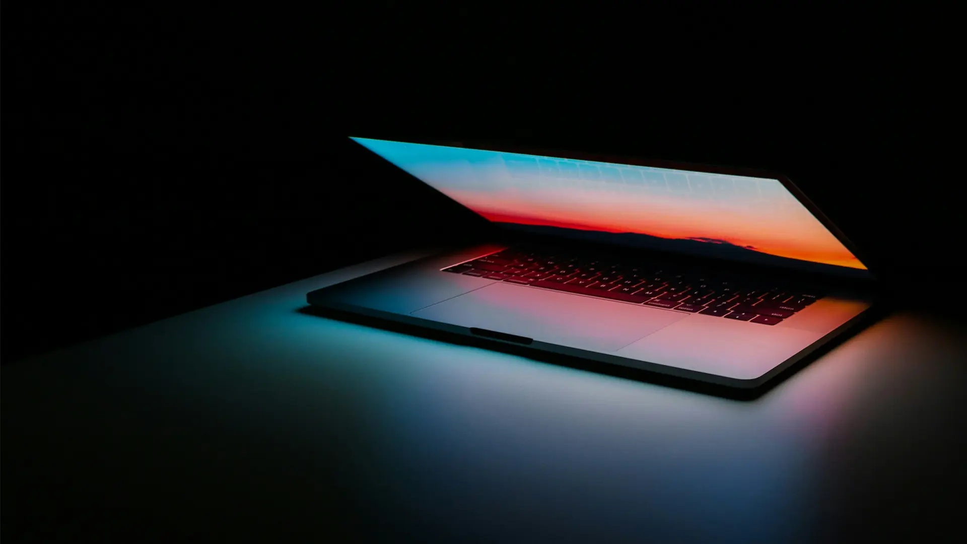 Ljuset från skärmen på en Macbook Pro lyser upp ett mörkt rum. 