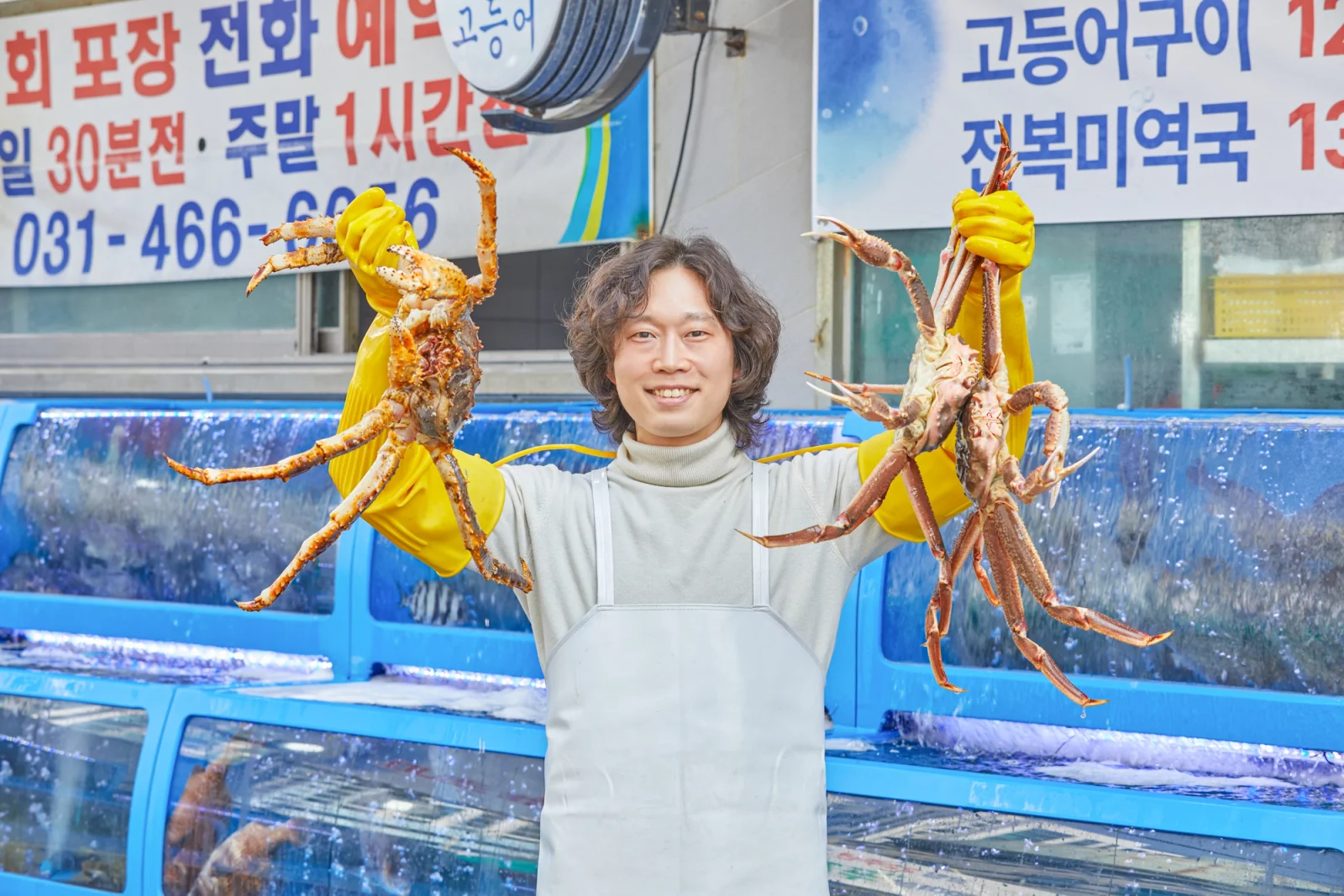 여자수산 안양본점 대표가 활게를 양손에 든 모습, 수족관 앞