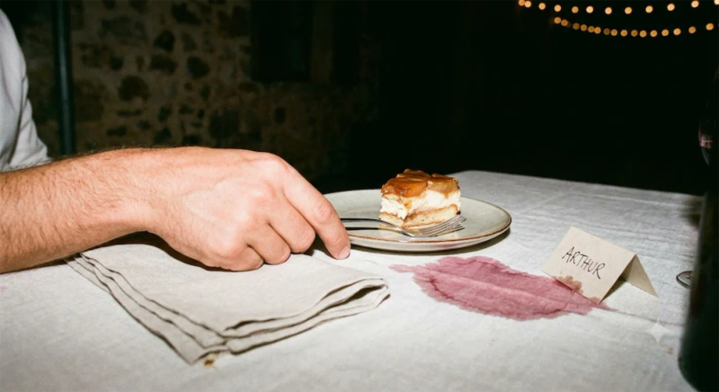 Une part de gâteau, une tache de vin sur la nappe et un marque-place au nom d’Arthur.