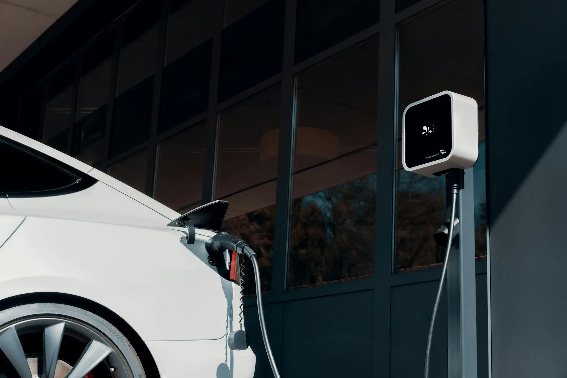 A white car plugged in to a charging station