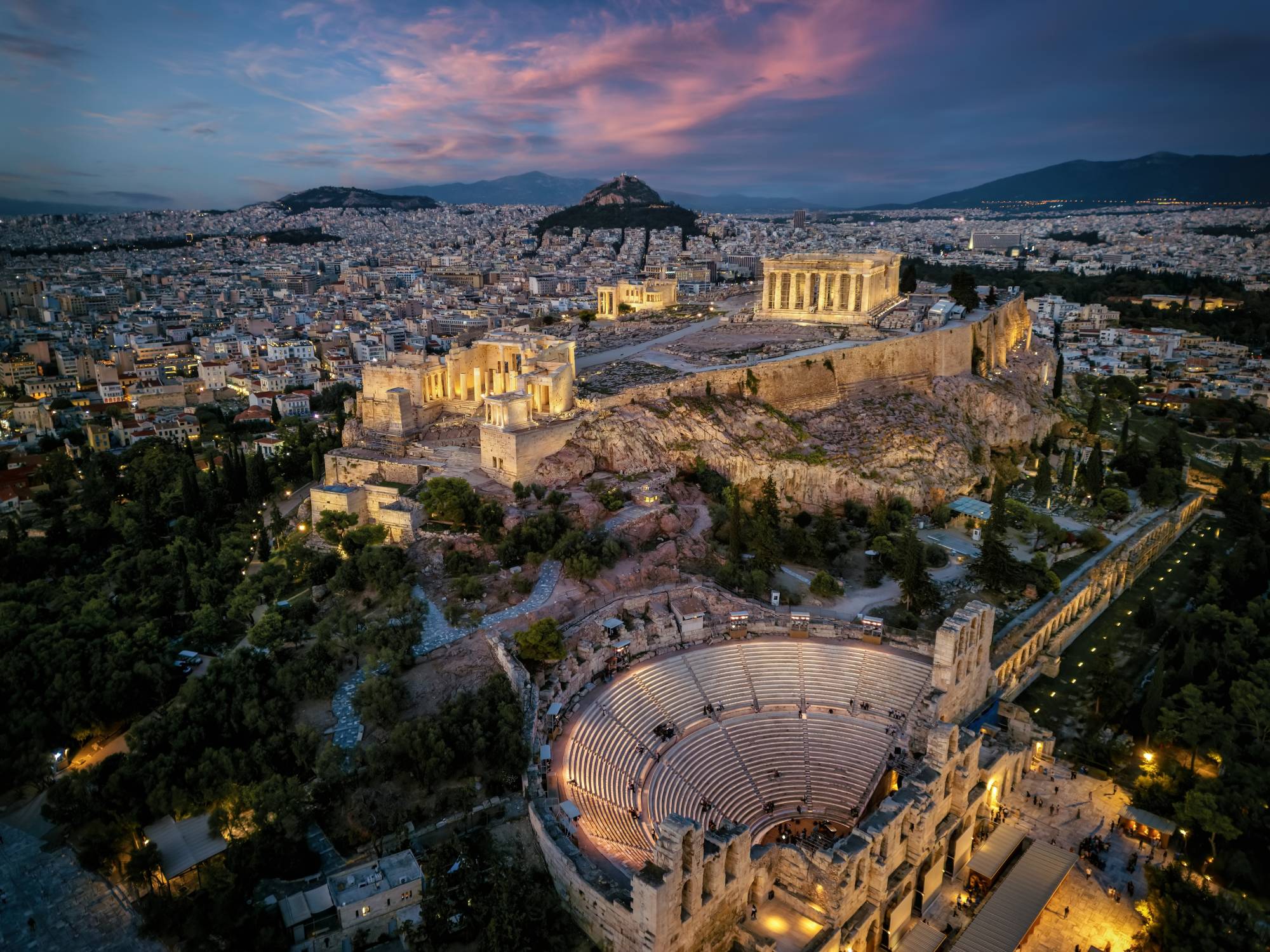 Aerial view of Athens Acropolis and Odeon of Herodes Atticus illuminated at dusk.