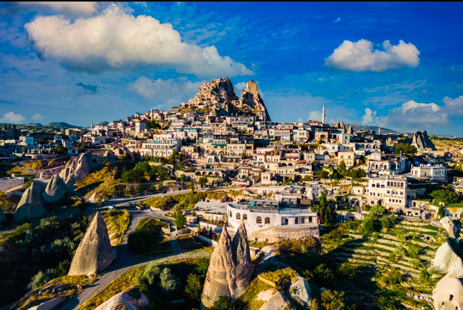 A hillside town with stone buildings surrounding a high volcanic rock fortress.
