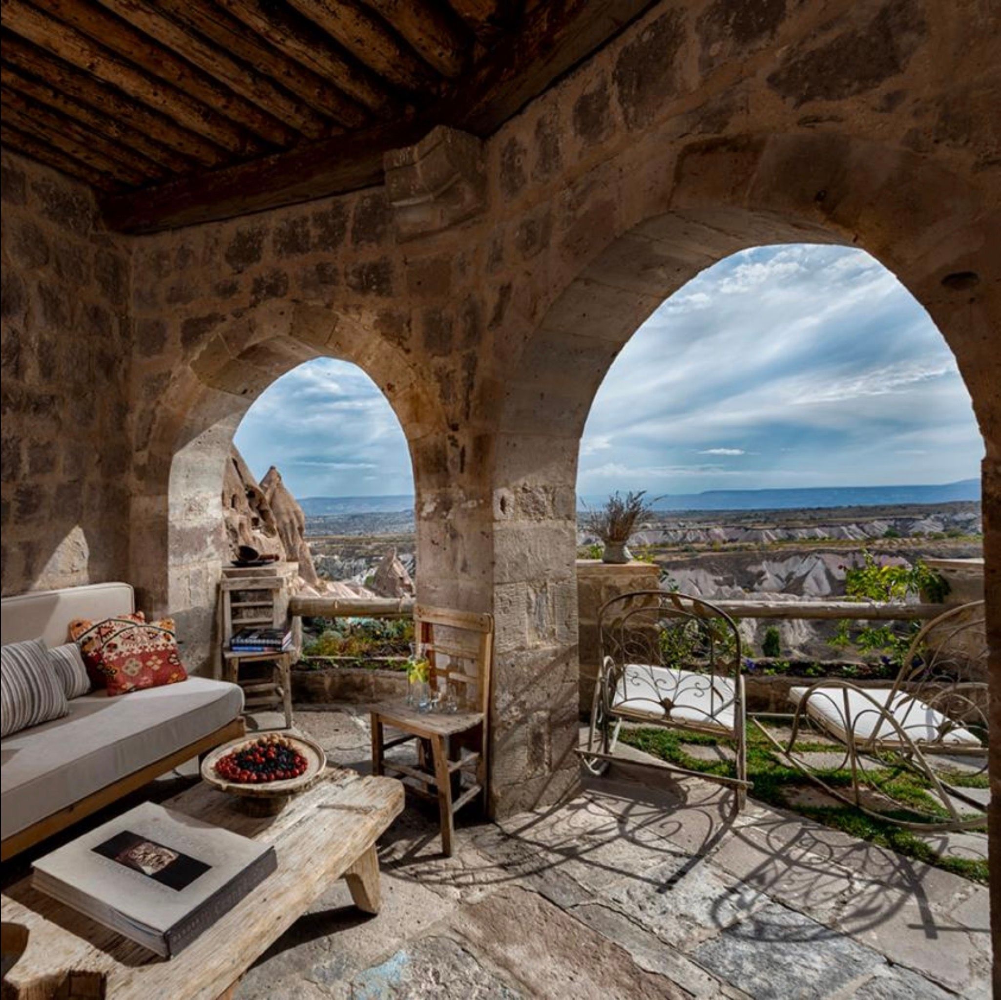 Stone arches frame a view of Cappadocia valleys from a furnished terrace.