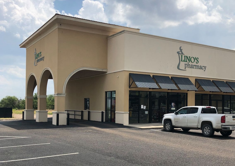 Lino's Pharmacy - A single-story building with a tan exterior and black awnings over windows