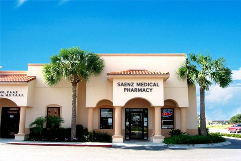 Saenz Medical Pharmacy - A pharmacy building with a beige exterior, arched windows, and palm trees in front
