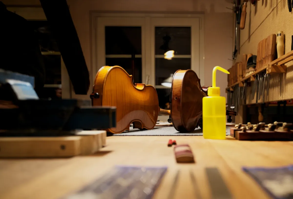 Deux instruments posés au fond de l'atelier, vus au ras de l'établi, devant le mur d'outils.
