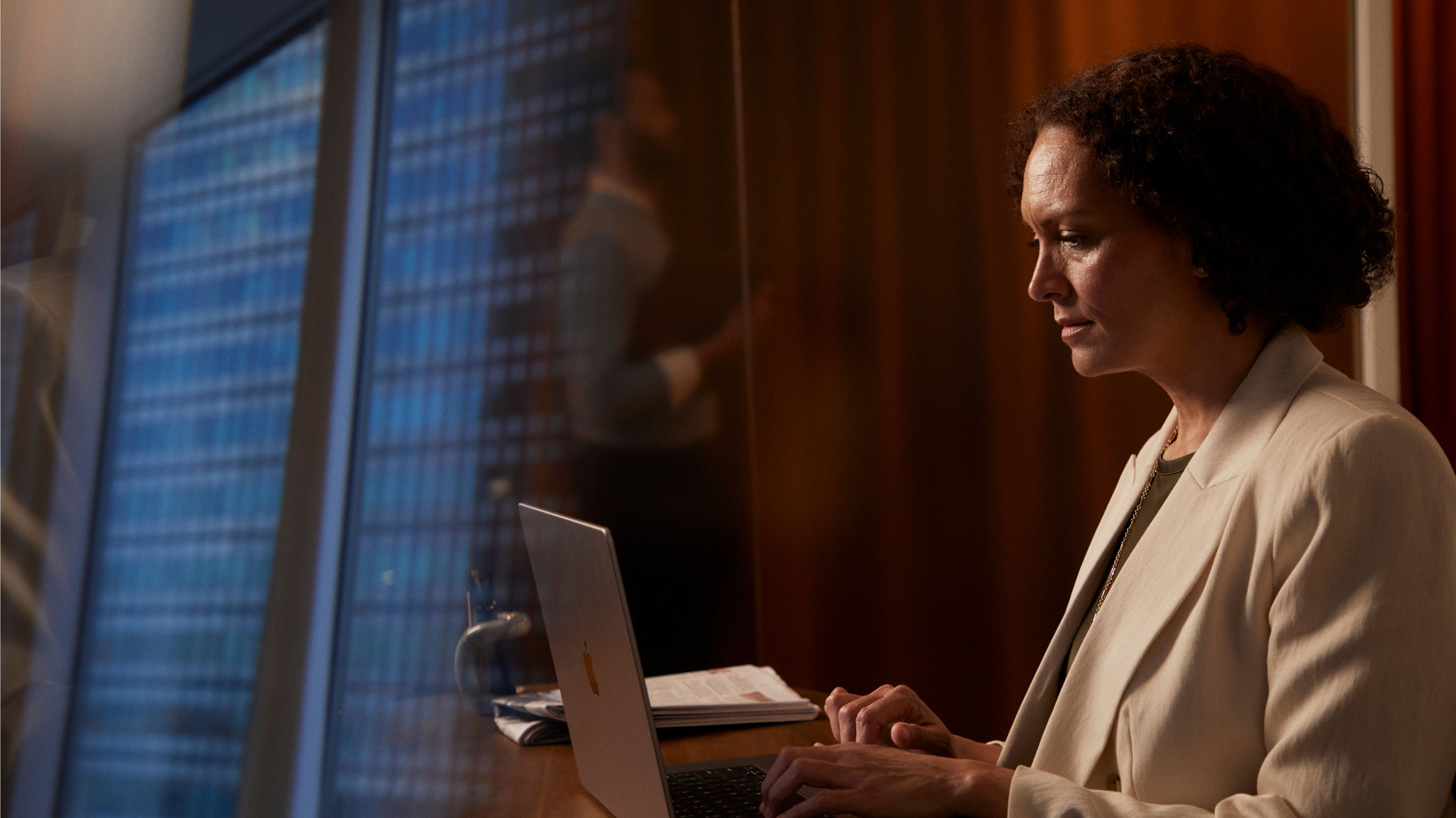 Lawyer working on a laptop in a glassy office with warm wood walls