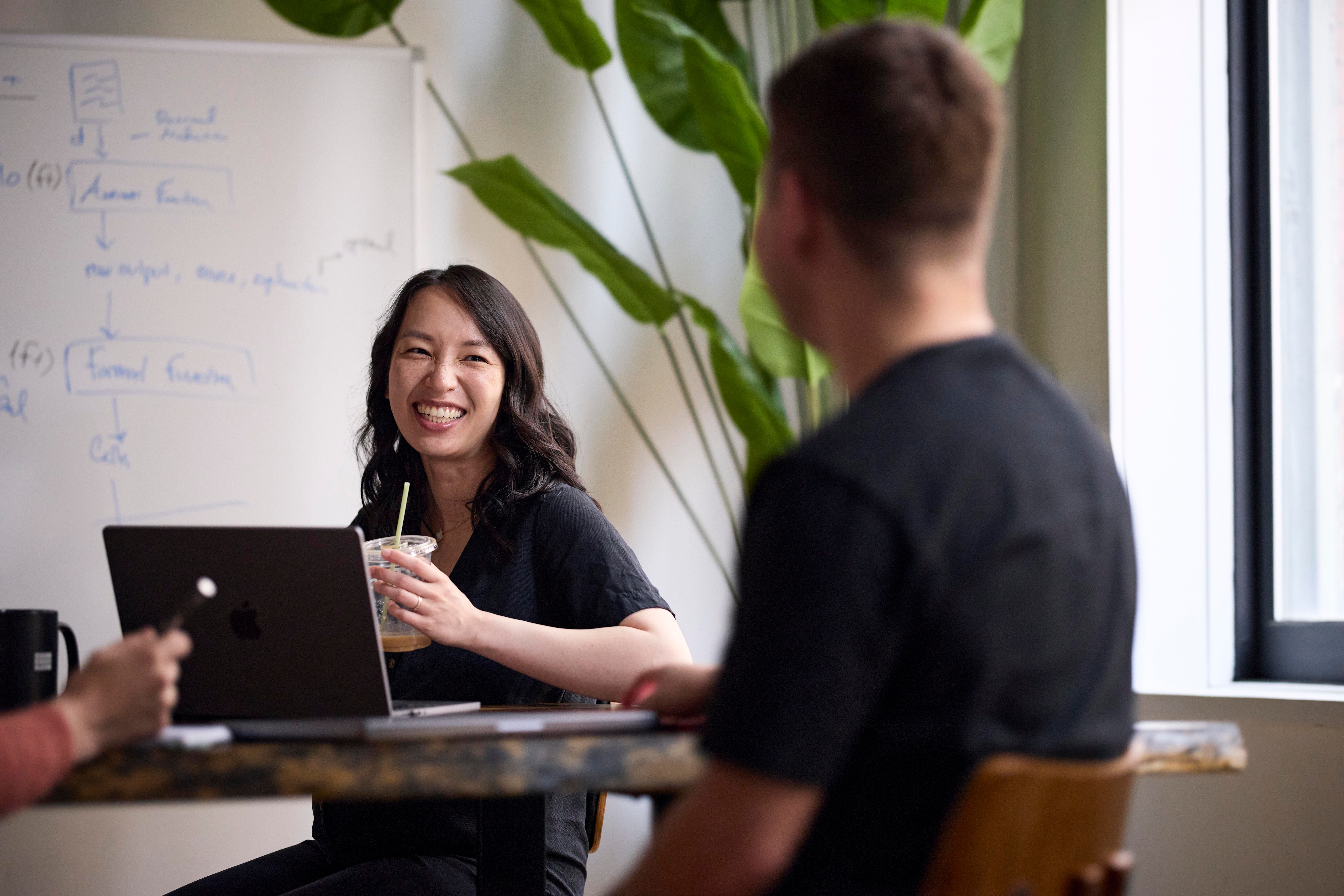 Two Harvey colleagues talking at a desk in front of a whiteboard