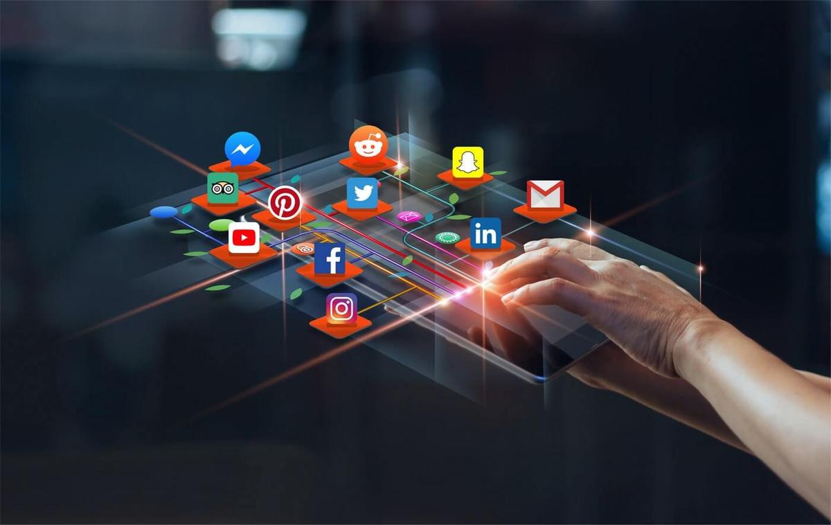Hand using a digital tablet with floating social media icons representing digital advertising and online marketing platforms.