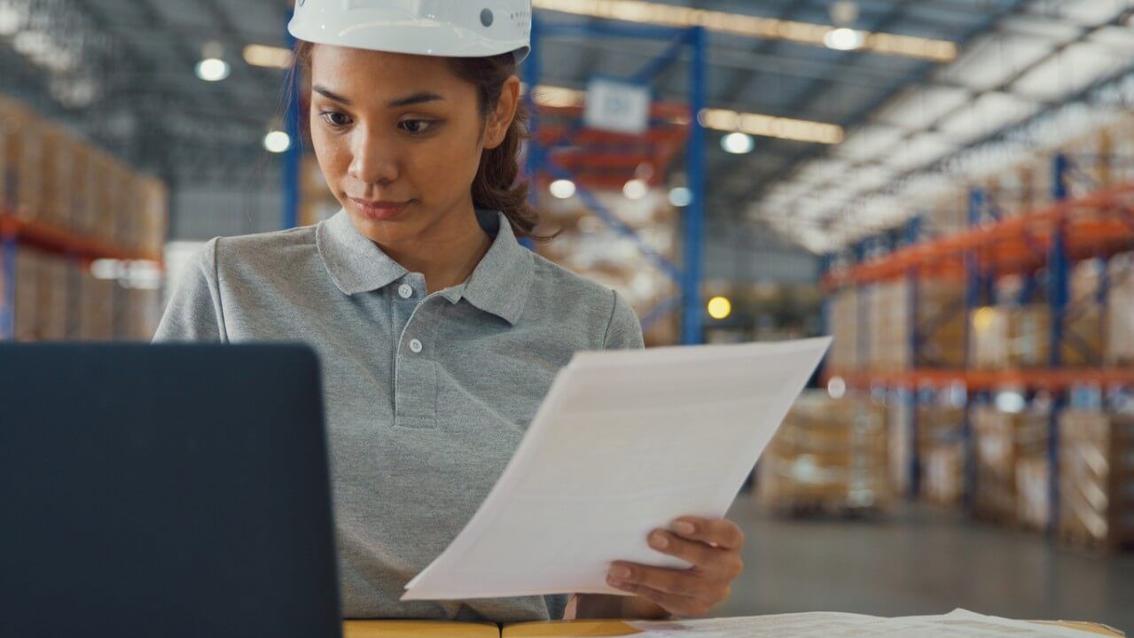Woman reviewing paperwork in a warehouse.