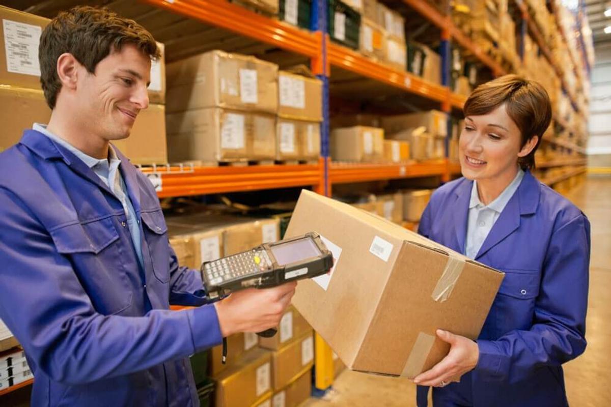 A man and a woman scanning a QR code in a warehouse.