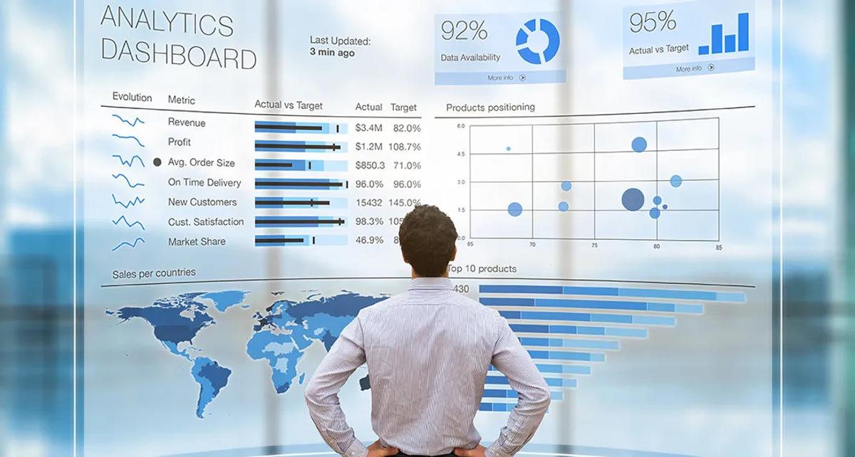 A man standing in front of a large screen displaying Analytics Dashboard and reporting.