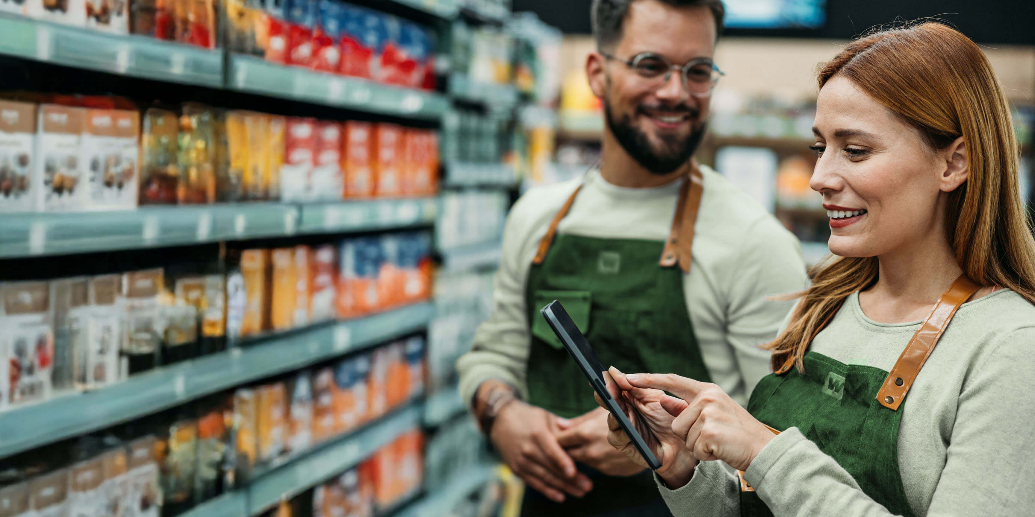 A woman holding a cellphone in a grocery aisle.