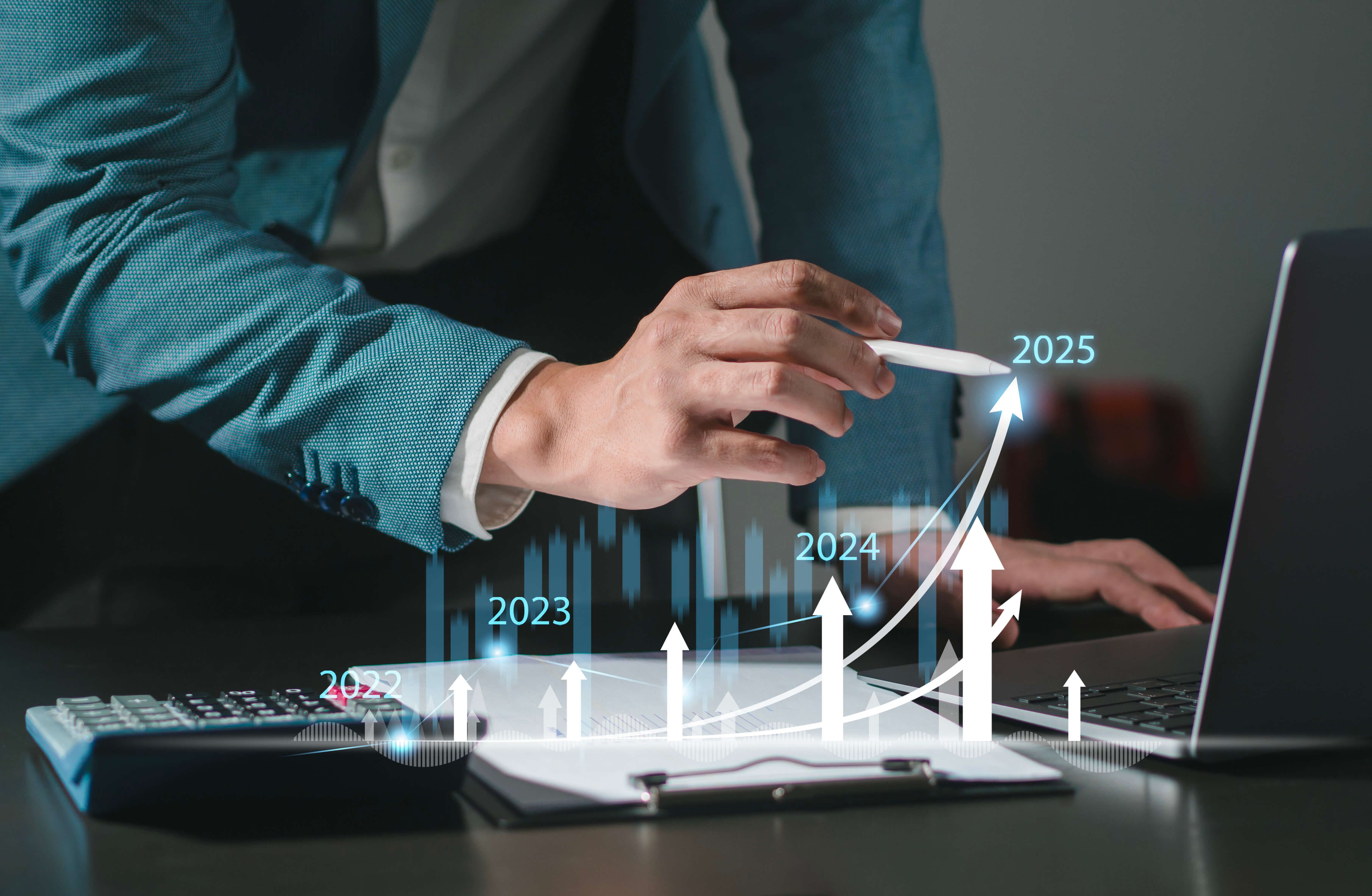 Man in a suit drawing a graph on a laptop.