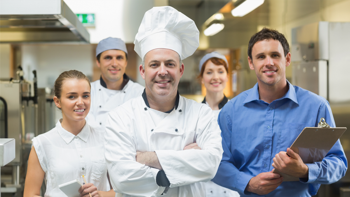 A group of people in chef's uniforms in the kitchen.