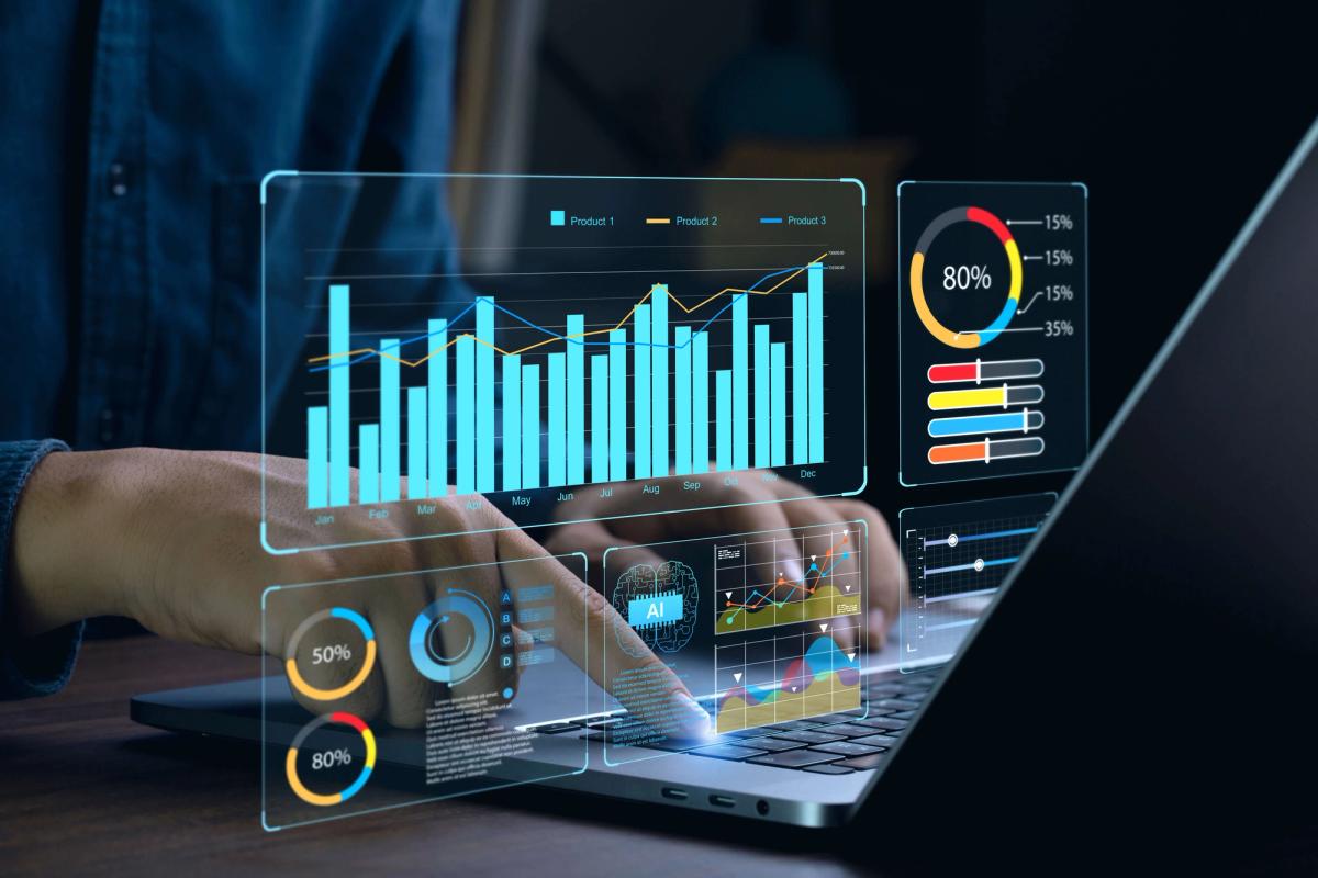 Person using a laptop with holographic data dashboards showing charts, graphs, and analytics insights.