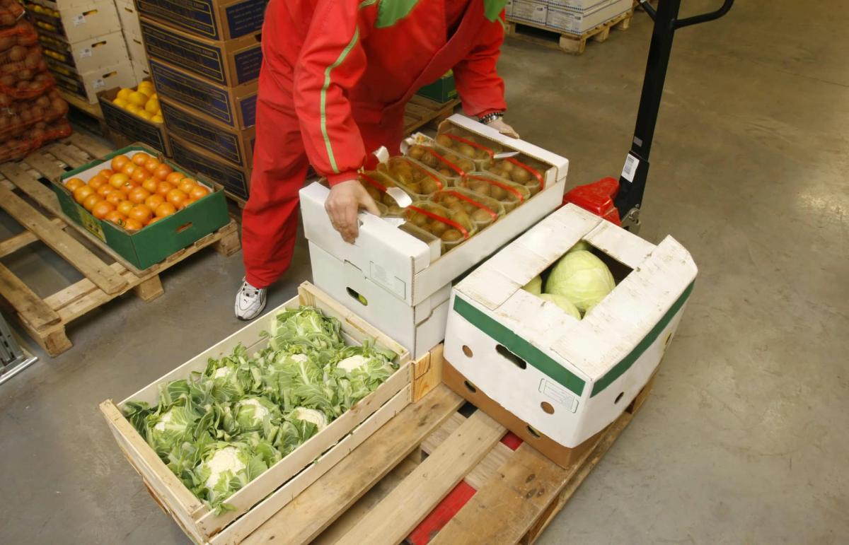 A person in a red jumpsuit putting food in boxes.