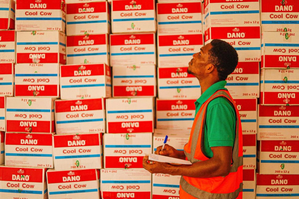 A man holding a notepad, doing inventory of stocks.