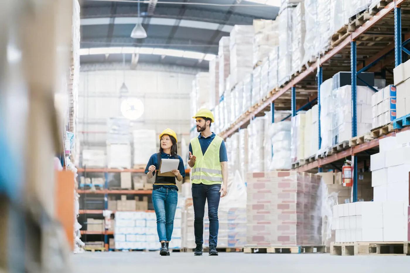 A man and a woman taking inventory in a warehouse.