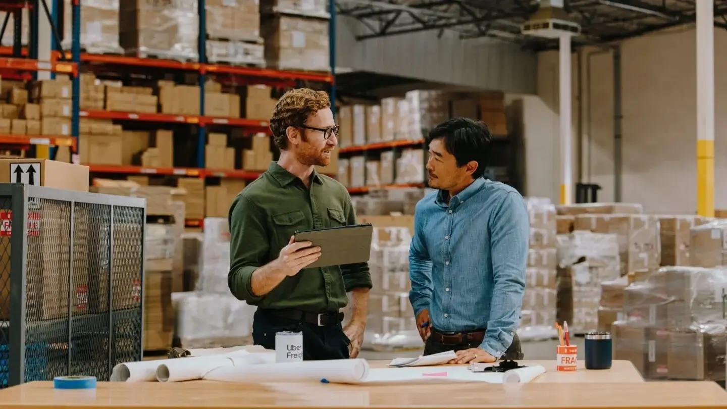 Two men discussing work in a warehouse.