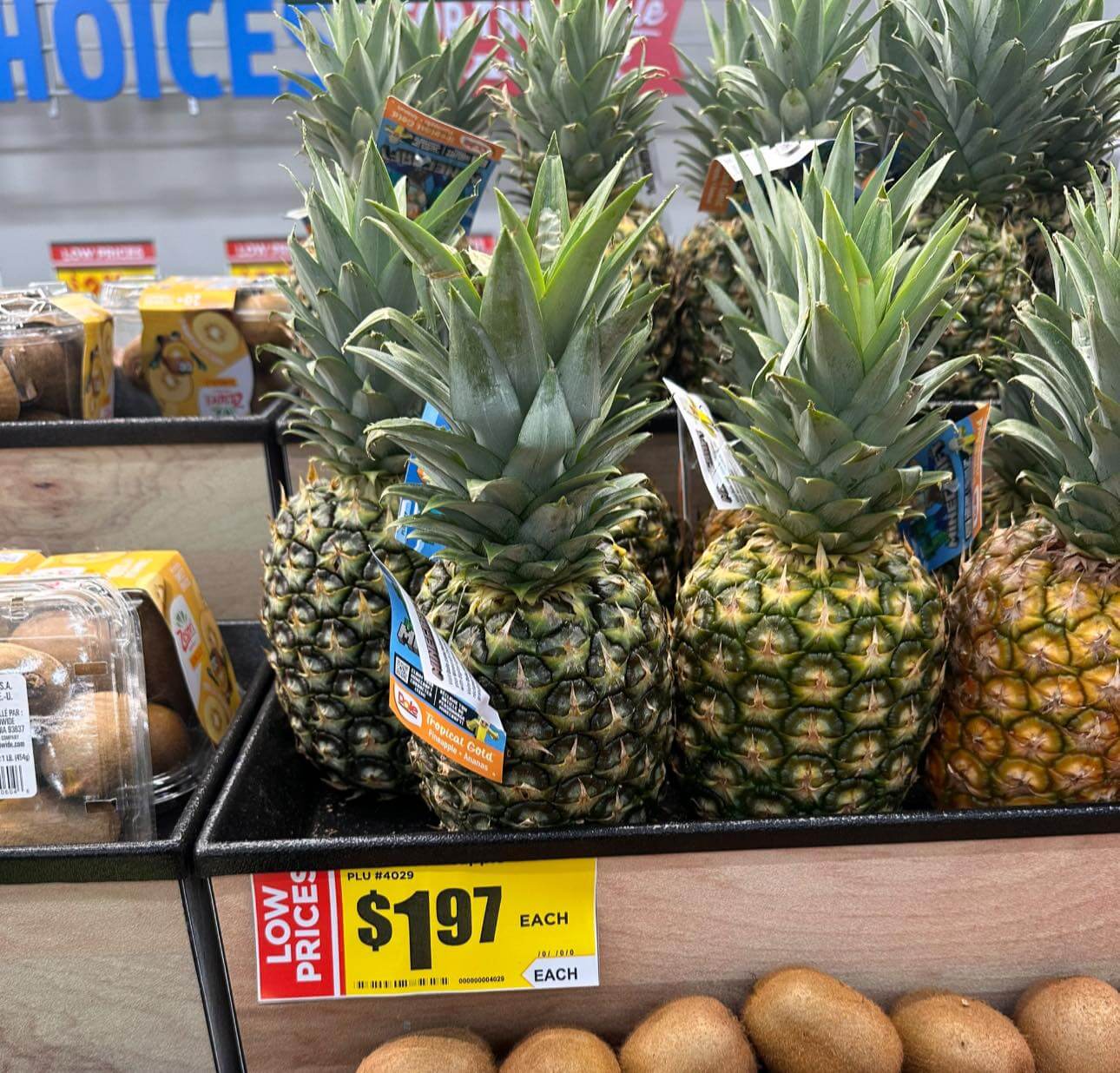 Pineapples on display with a $1.97 each sale sign in a grocery store.
