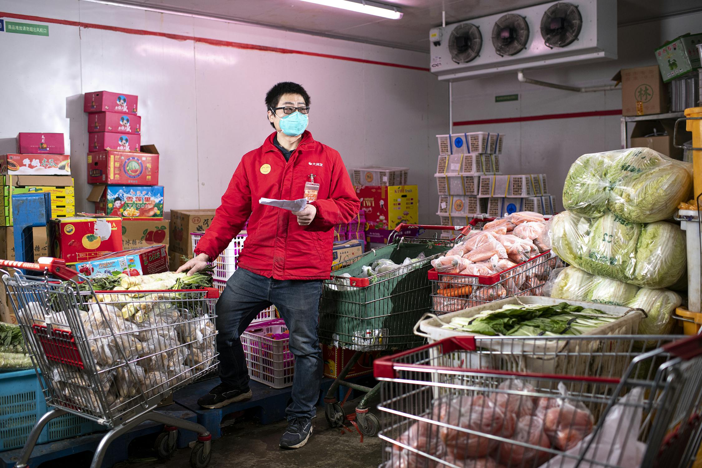 Man in a stockroom organising carts filled with fresh produce.