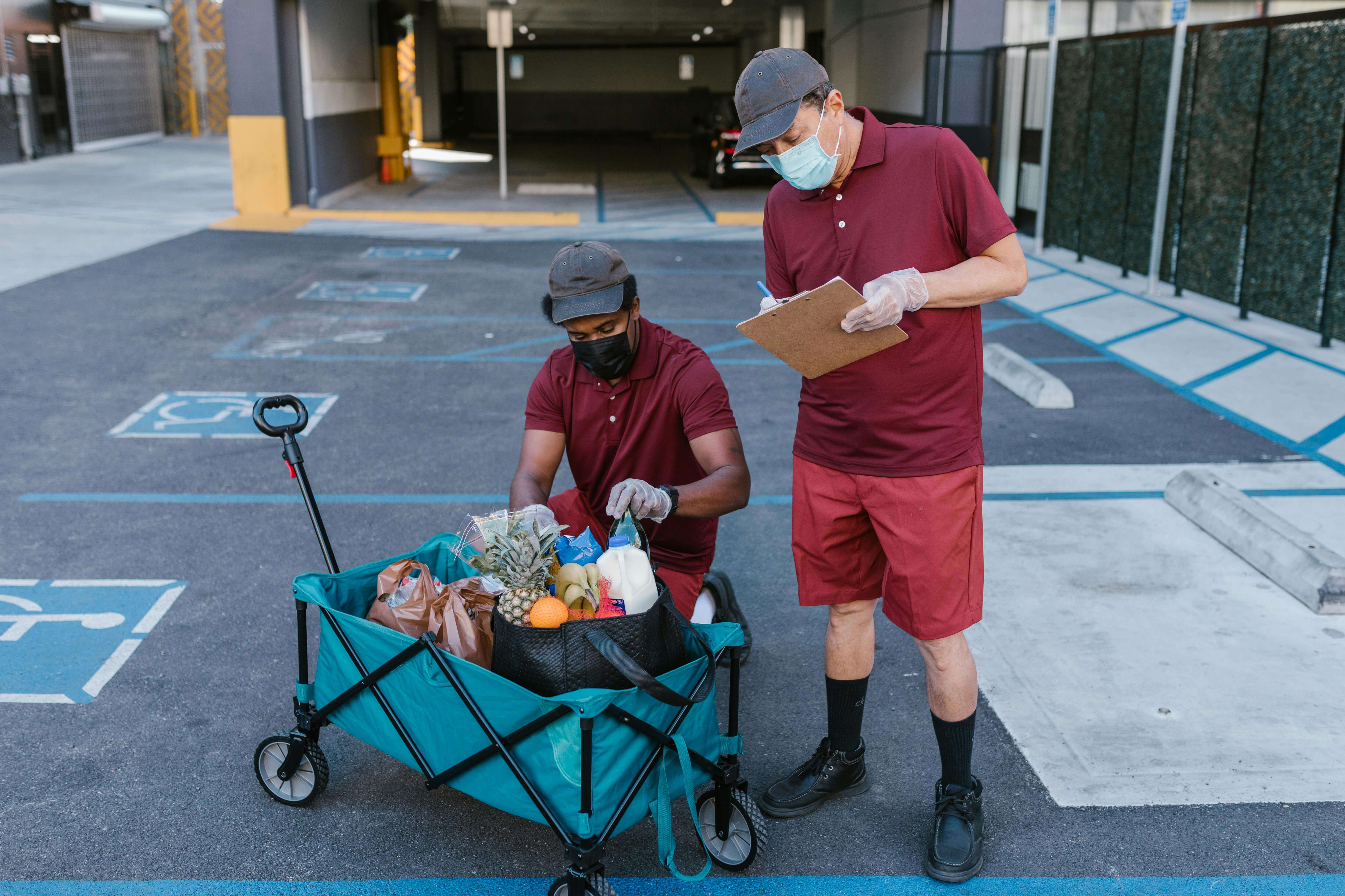 Man in red crew neck t-shirt and black pants holding black and gray stroller.
