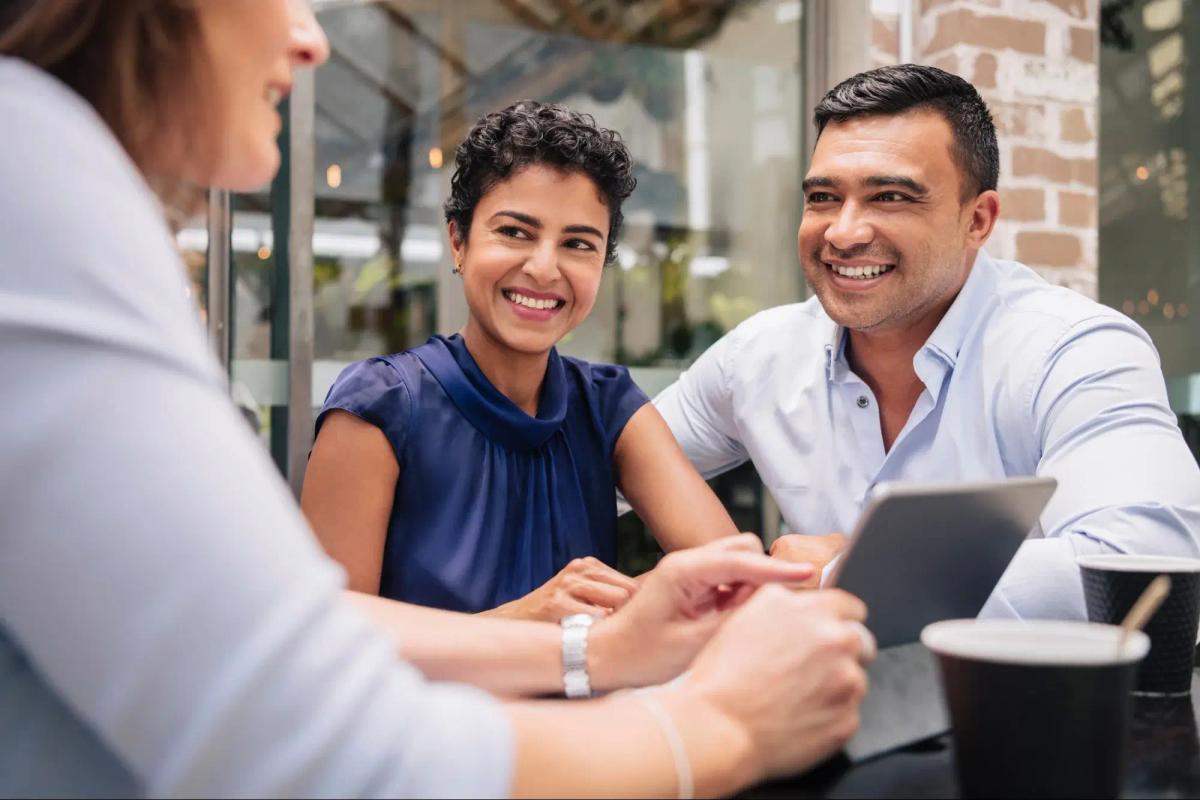 Three happy people discussing business, indicating strong customer relationship.