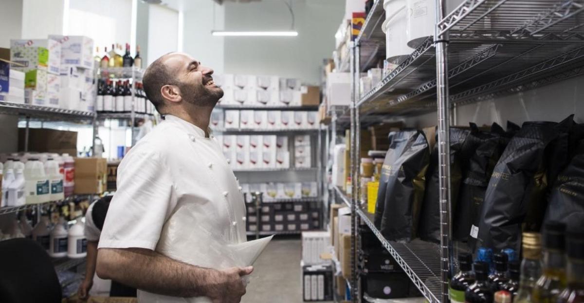 A chef standing in a restaurant storage area tracking the inventory.