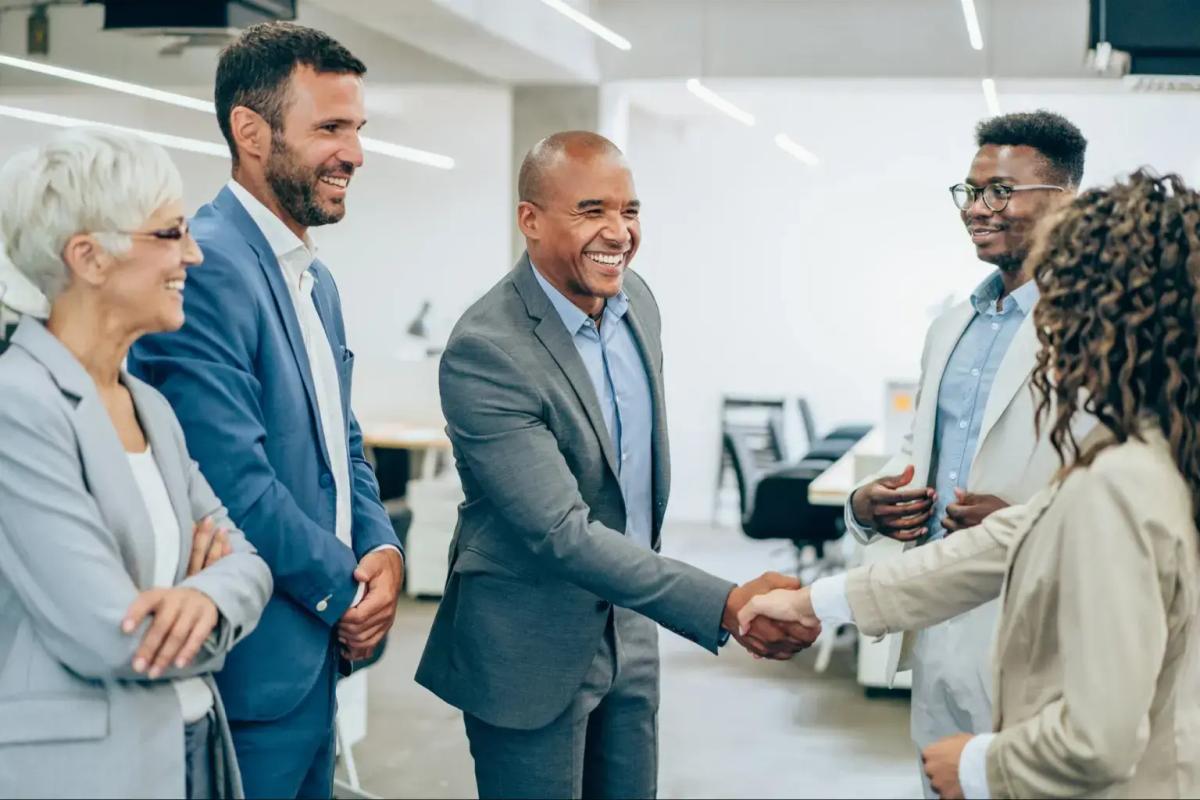 Business team smiling and shaking hands during an office meeting.