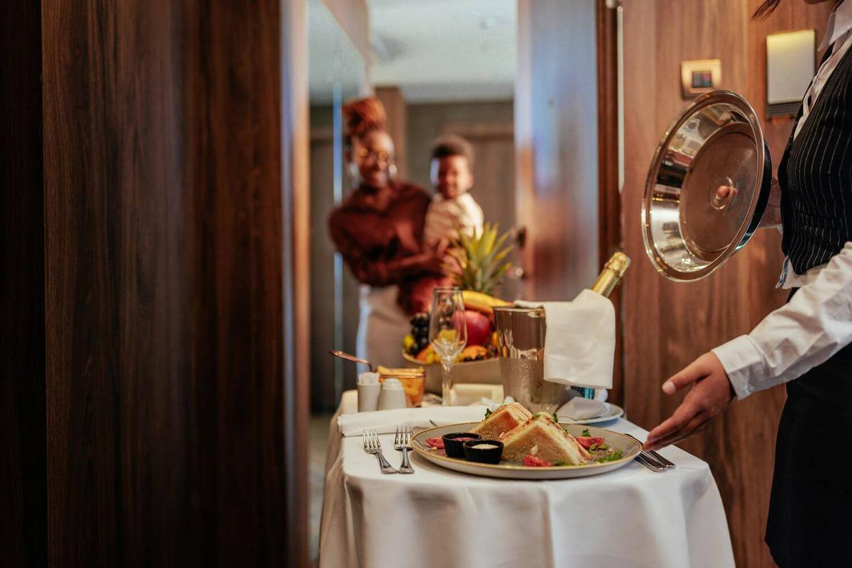 Woman serving a food using a trolley in a hotel, representing hospitality operations.