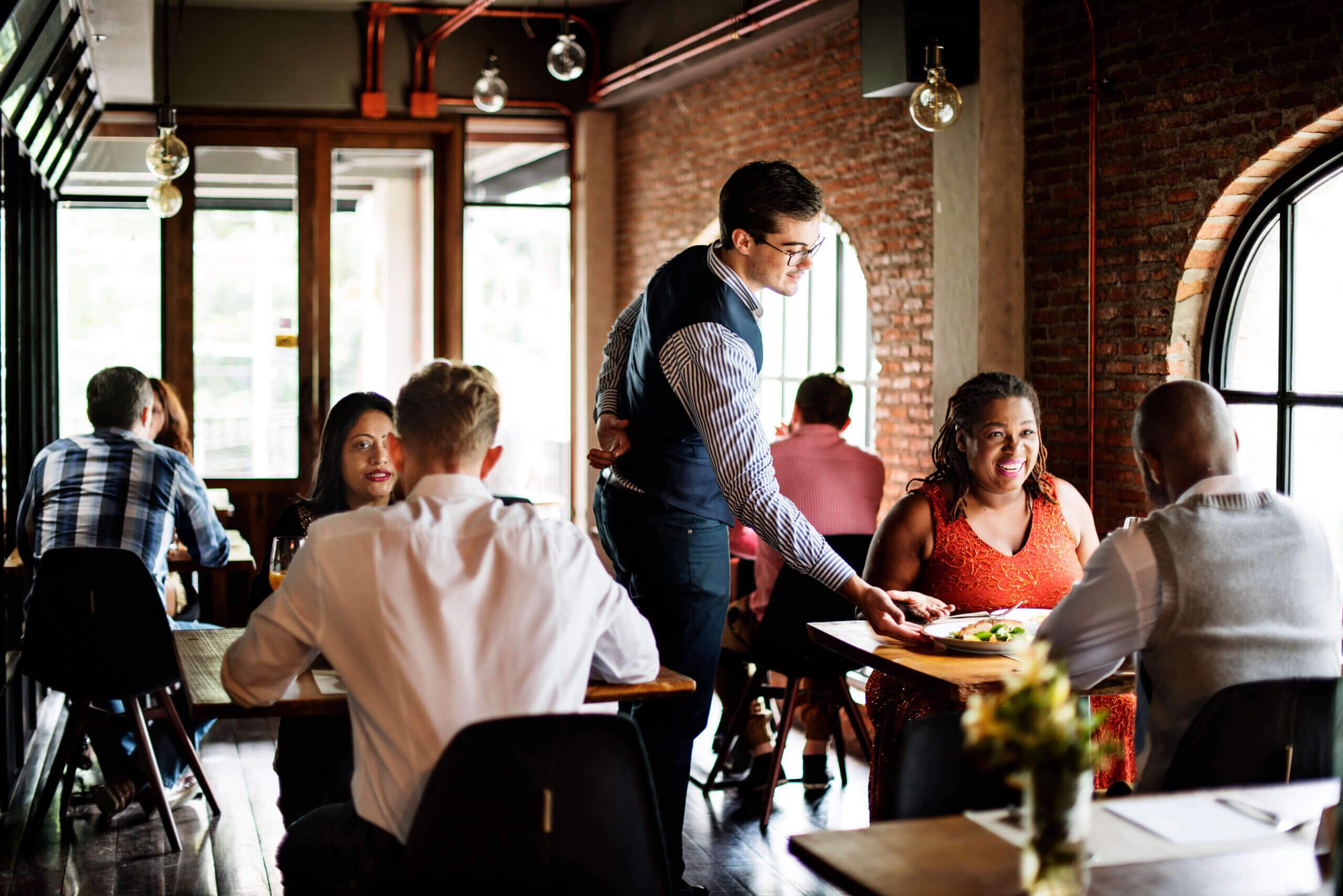 Restaurant staff delivering meals to diners at their table.