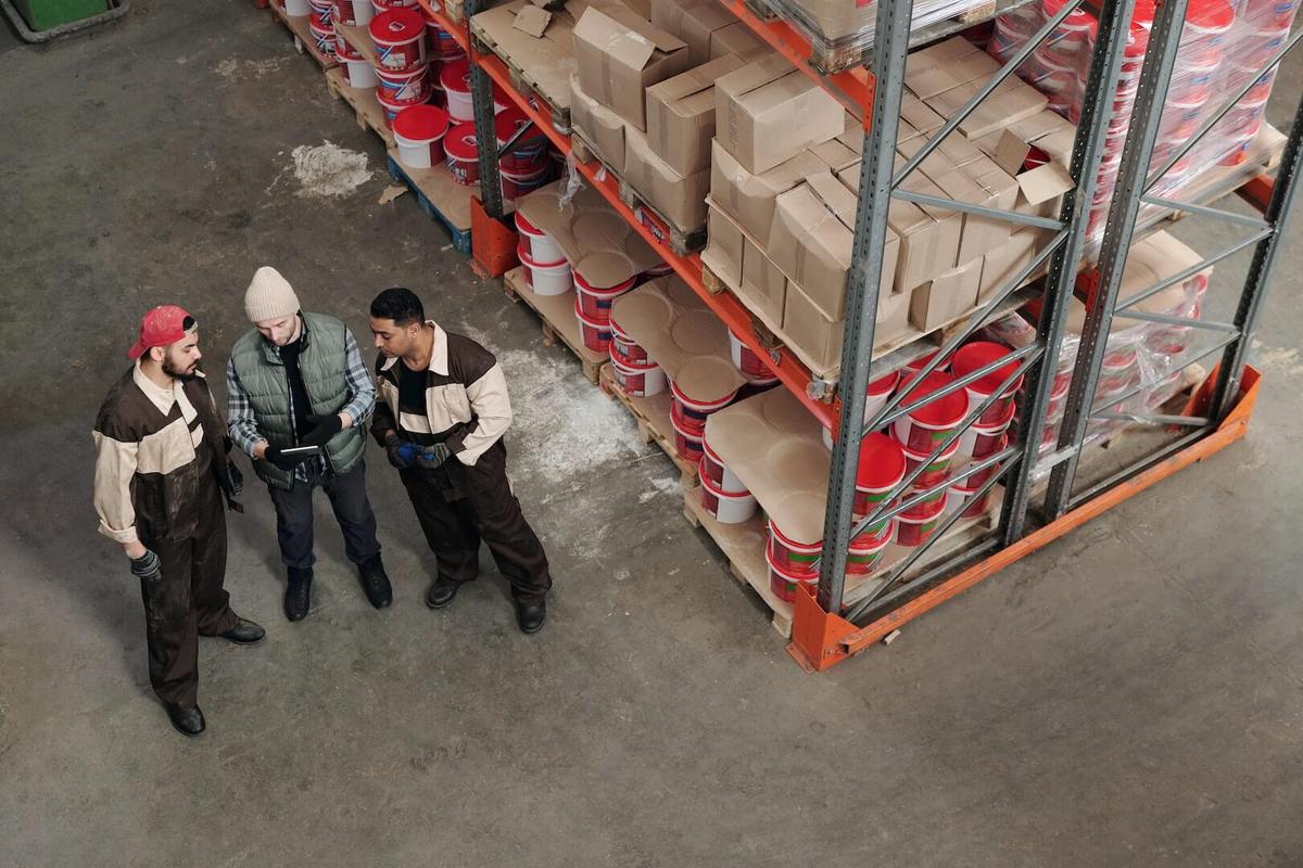 Three men discussing in a warehouse.