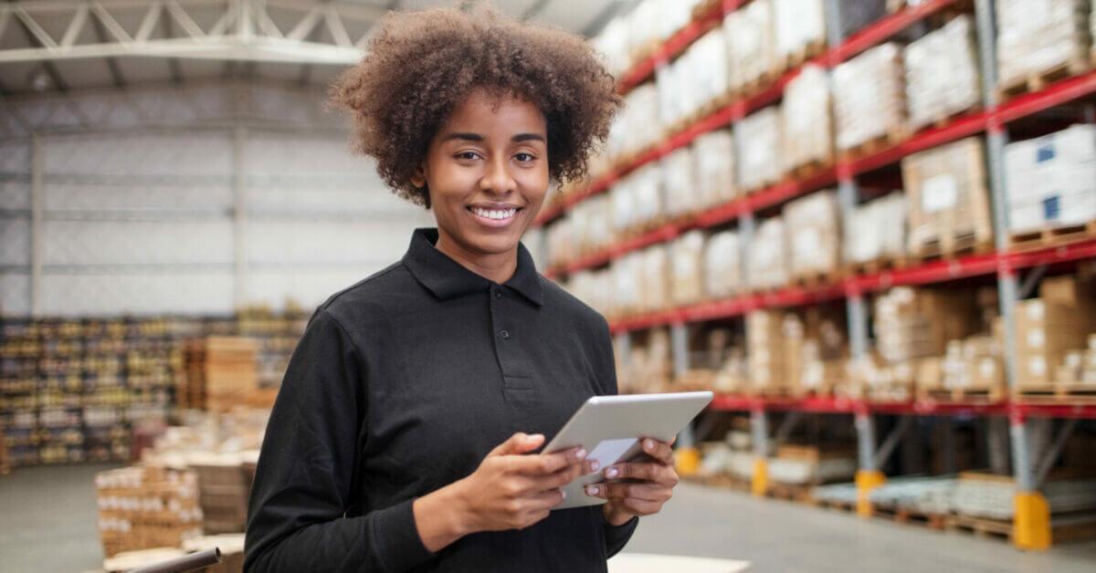 A woman holding a tablet inside a warehouse.