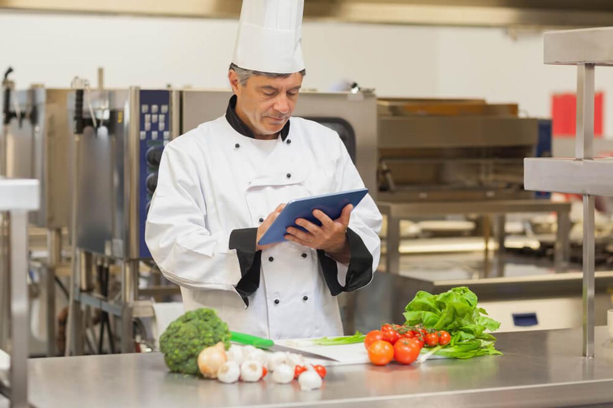 A chef holding a tablet to order online.