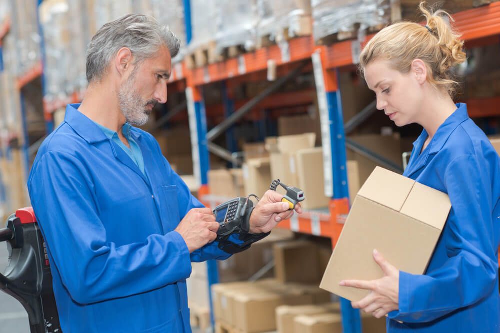 Warehouse workers using a barcode scanner and box in a warehouse.