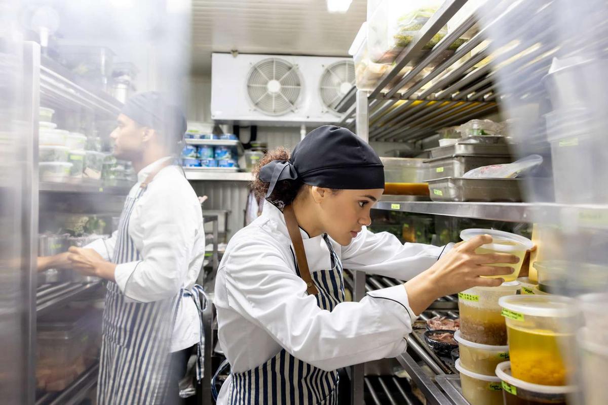 Chef wearing hat and apron while working in a kitchen.