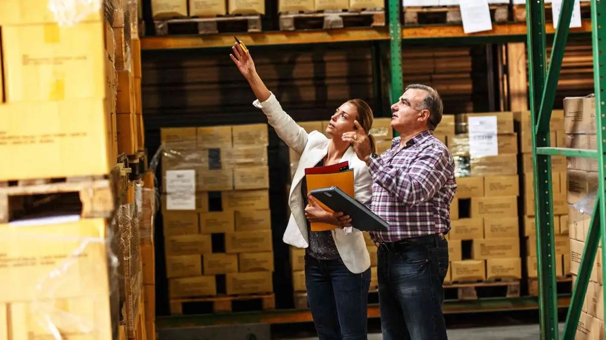 A man and a woman taking manual inventory in a warehouse.